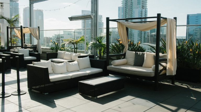 Luxurious rooftop patio with comfortable modern seating, plants, and city skyline views.